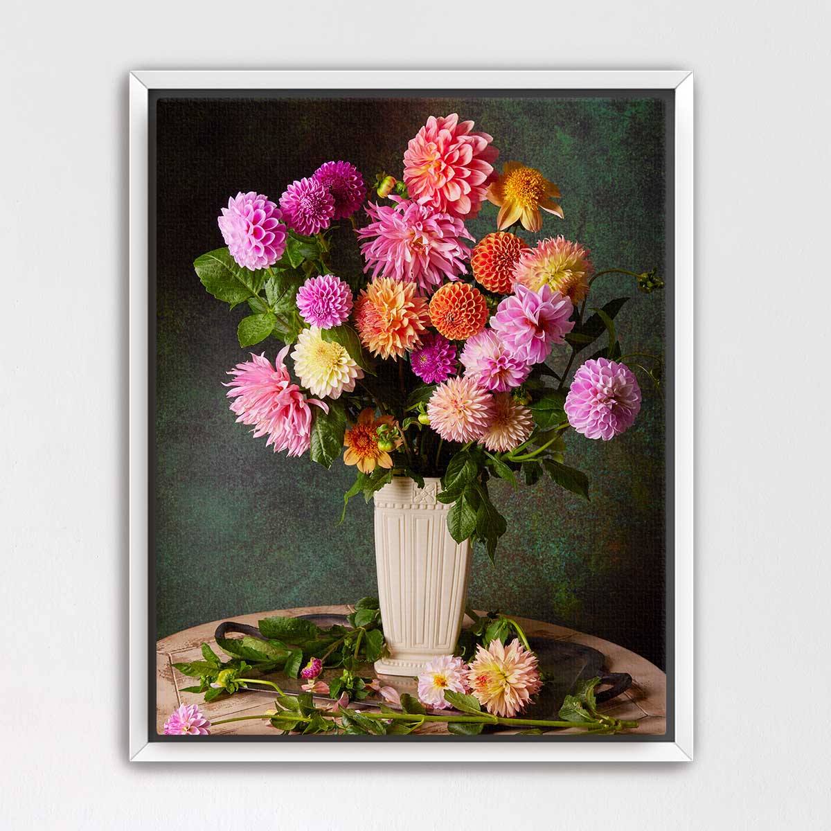 A bouquet of vibrant dahlias in a white vase, set against a dark green background.