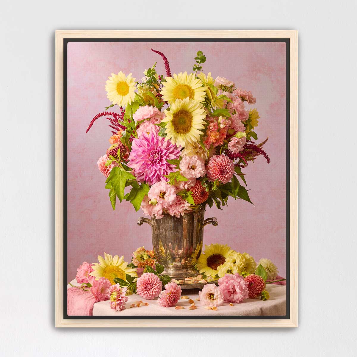 A framed photograph of a vase filled with a vibrant bouquet of colorful flowers, including sunflowers, dahlias, and other blooms, set against a pink background.