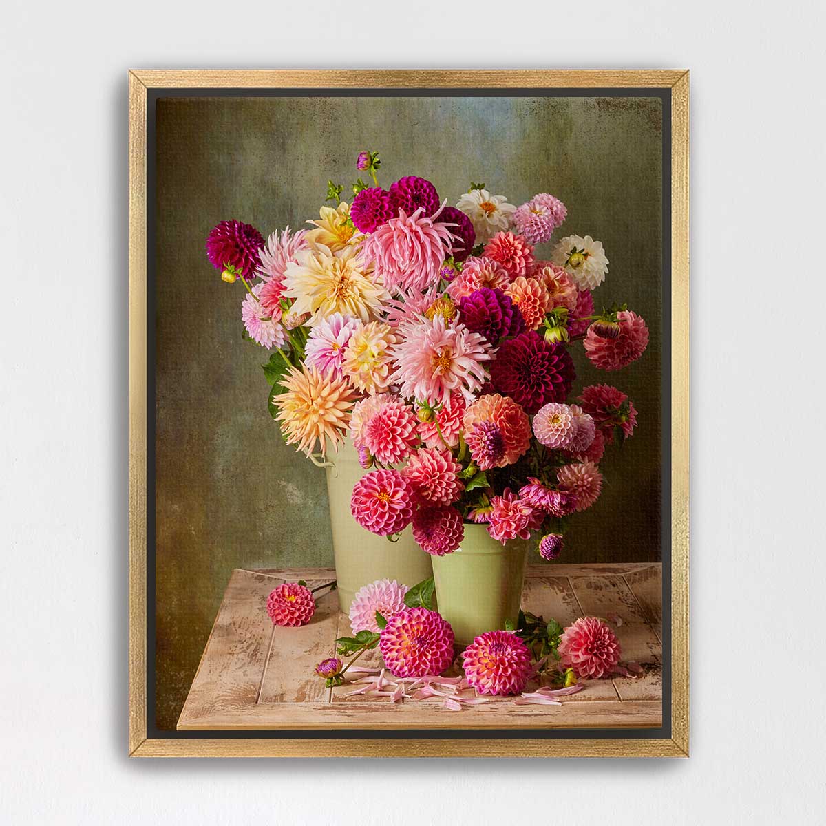 A framed image of a bouquet of colorful dahlias in two green vases, placed on a wooden table against a green background.