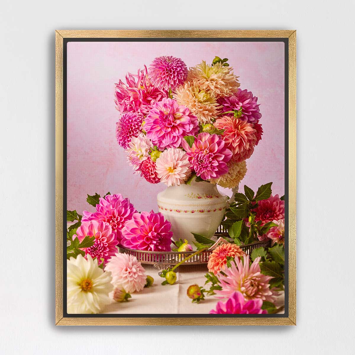 A framed image of a bouquet of pink and yellow dahlias in a white vase, surrounded by additional flowers on a table.