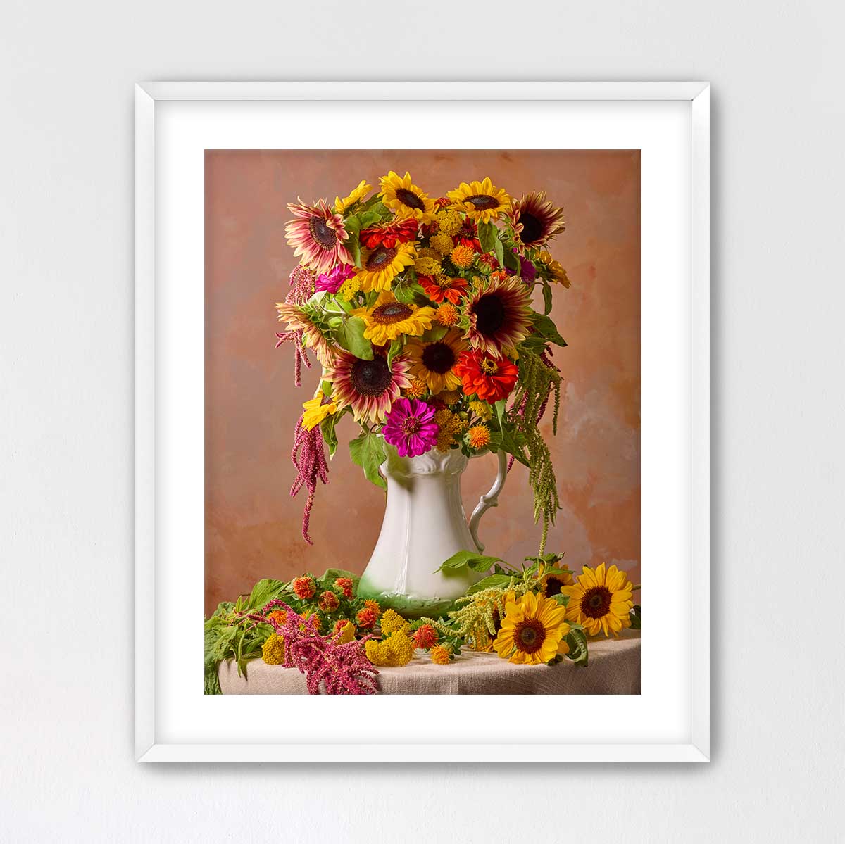 A white vase filled with a vibrant bouquet of sunflowers and other colorful flowers sits on a table, creating a cheerful and inviting atmosphere.