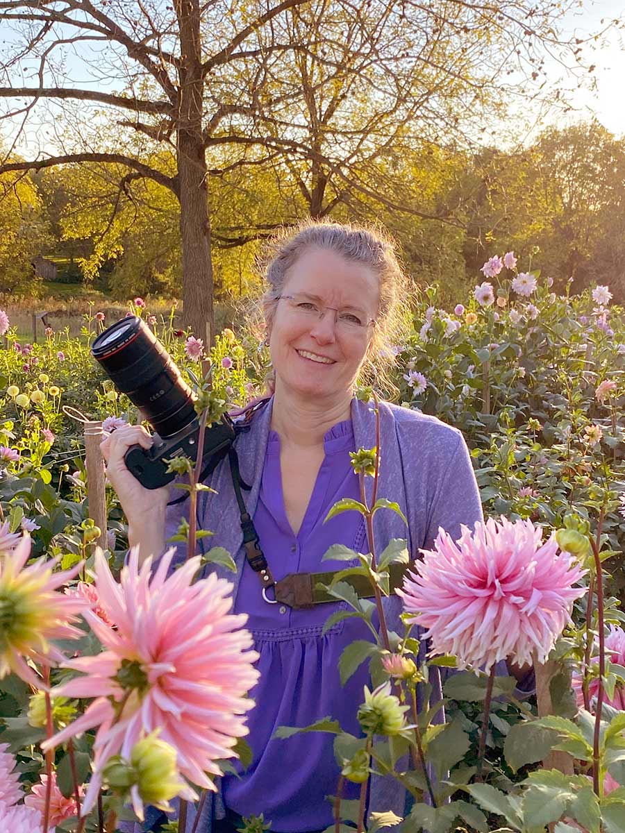 Image of Christina Peters fine art photographer in a flower field holding her camera