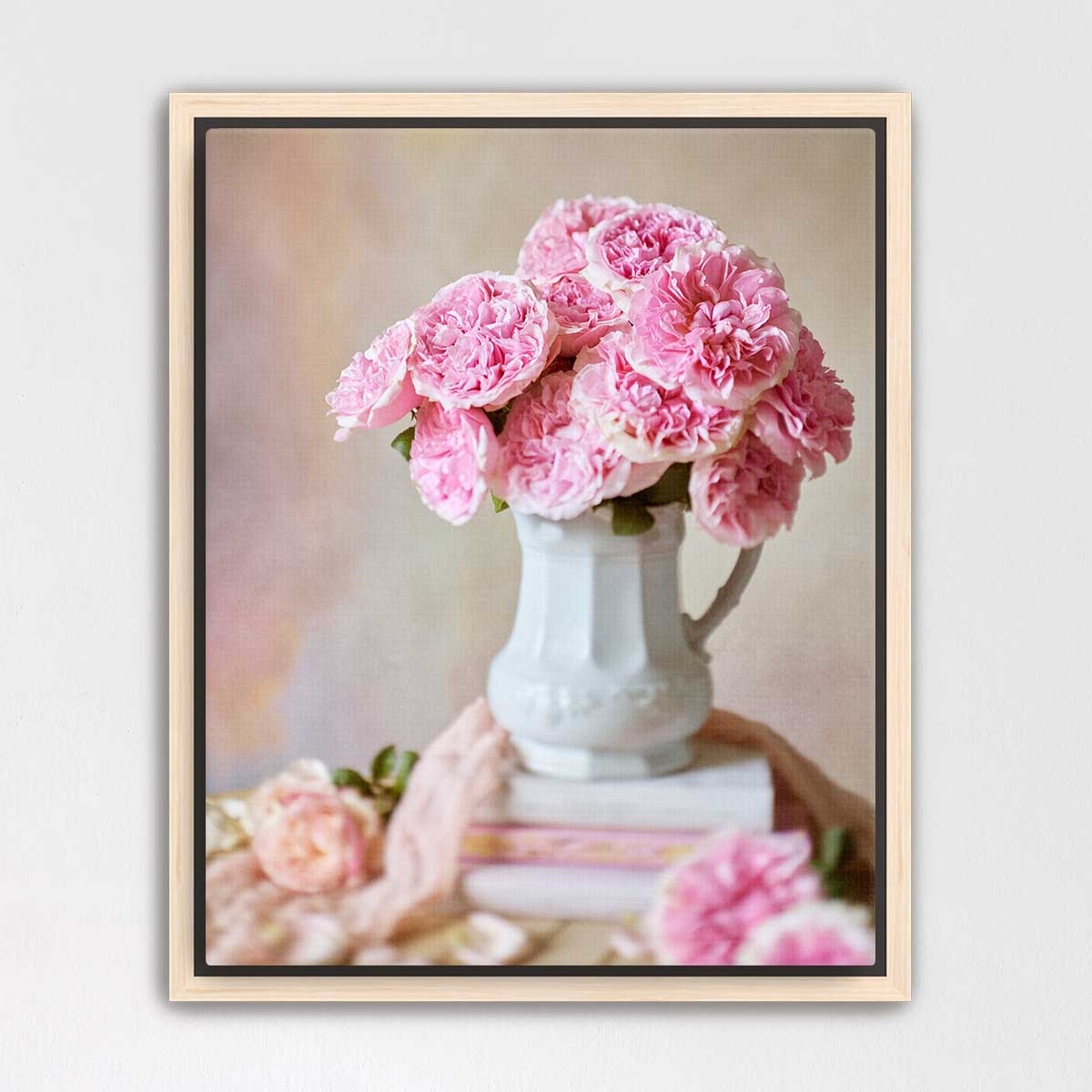 A white vase filled with pink carnations sits on top of a stack of books, creating a charming and elegant still life composition.