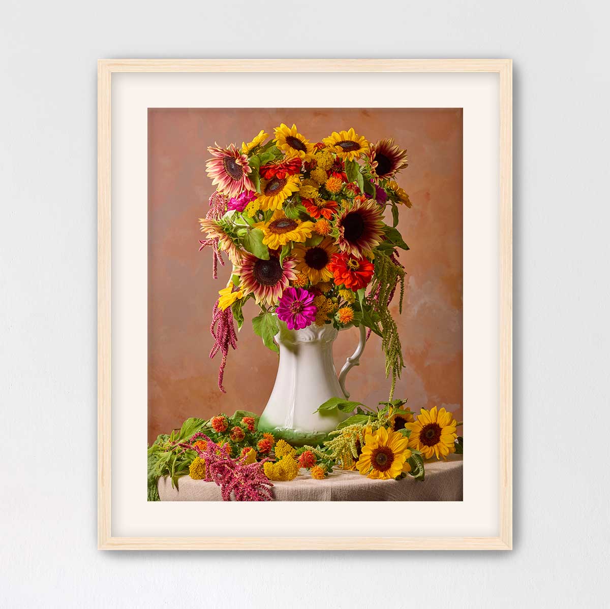 A framed image of a vase filled with a vibrant bouquet of sunflowers and other colorful flowers, placed on a table.