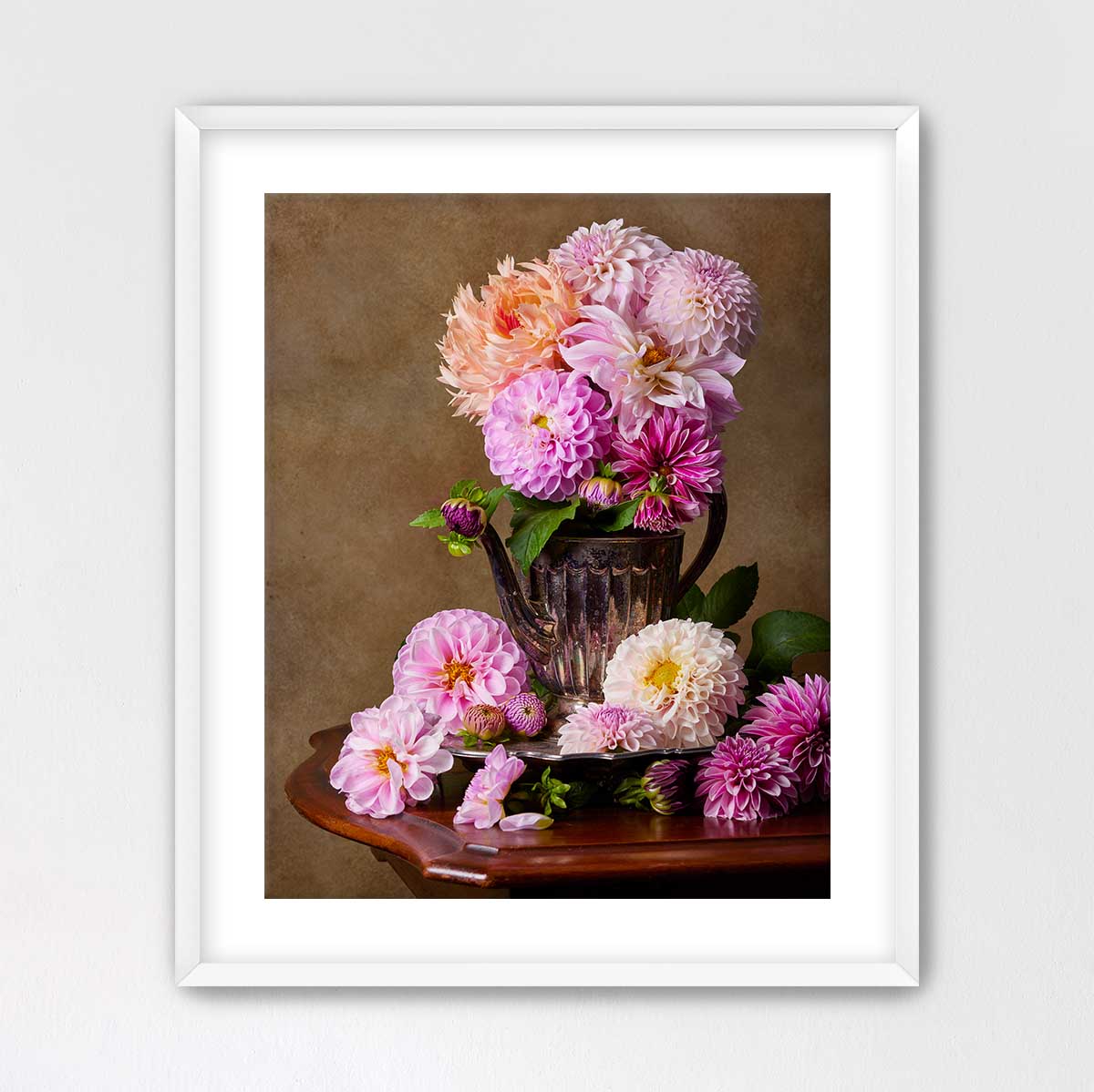 A framed image of a vase filled with a variety of colorful dahlias, including pink, orange, and white flowers, placed on a wooden table.