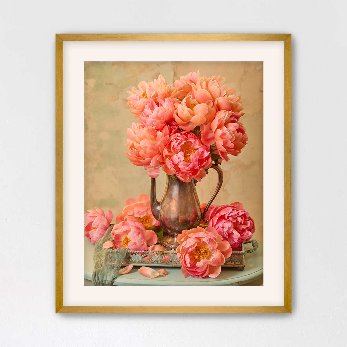 A framed image of a vase filled with vibrant pink peonies, placed on a small table.